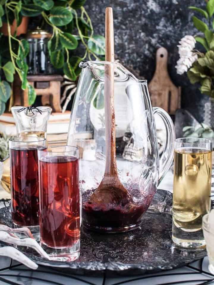 Pouring the juices into the pitcher with muddled blackberries for Halloween Punch.