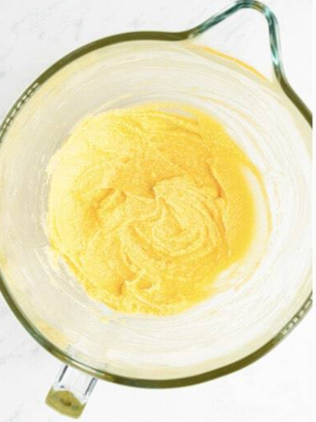 Butter and sugar creamed together in a glass mixing bowl for Halloween sugar cookies.