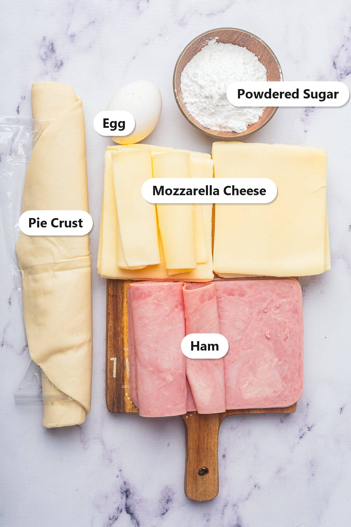Labeled ingredients for Ham and Cheese Bars including pie crust, mozzarella cheese, ham, egg, and powdered sugar.