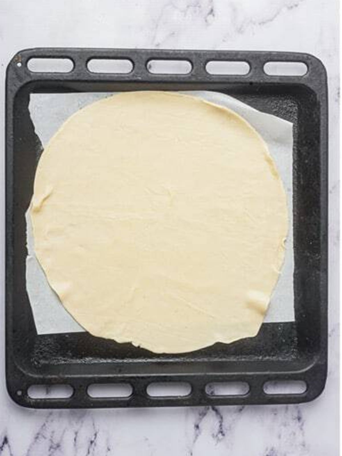Rolling pie crust onto a parchment-lined baking tray for Ham and Cheese Bars.