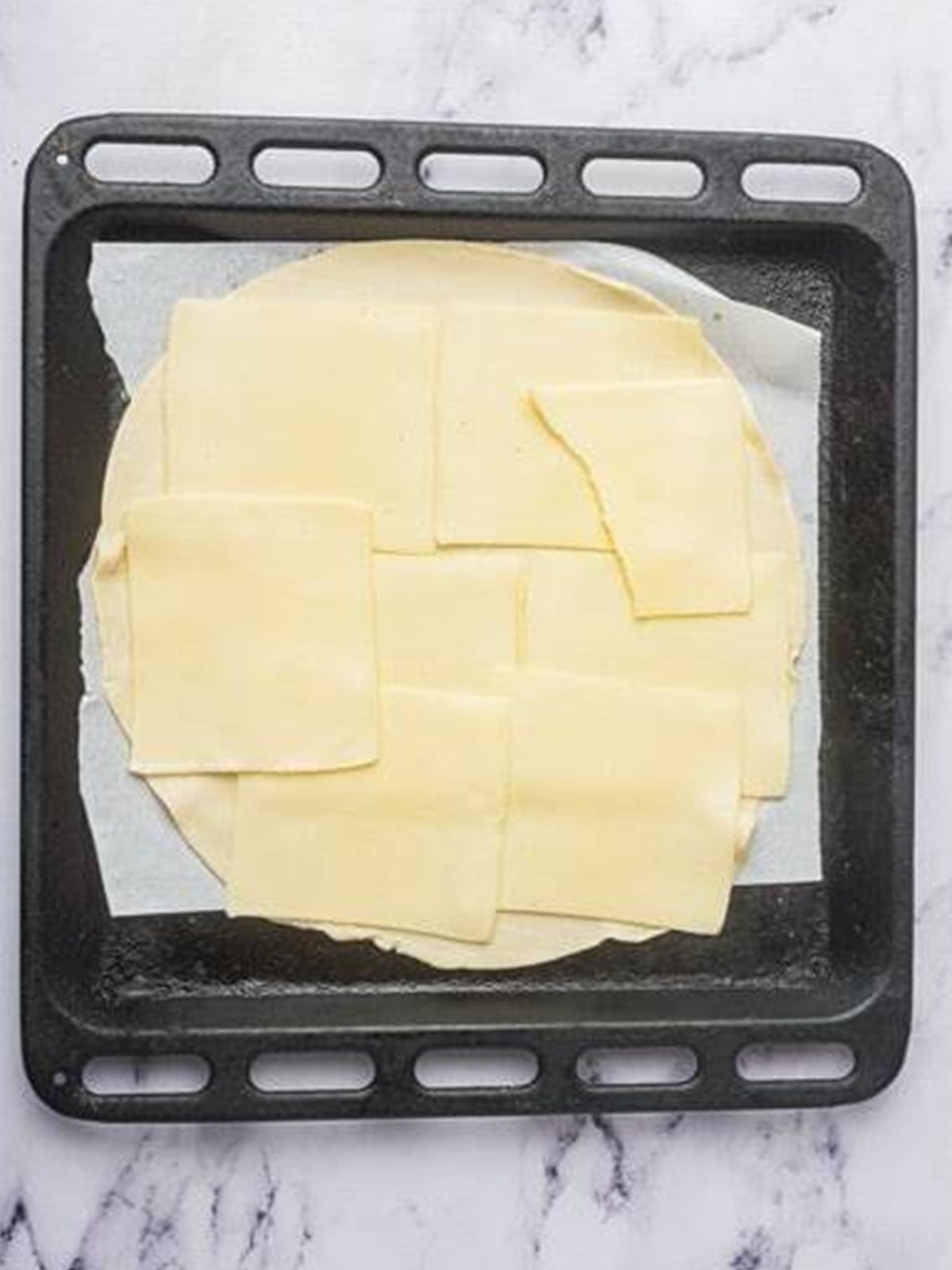 Layering mozzarella cheese slices over the pie crust for Ham and Cheese Bars.
