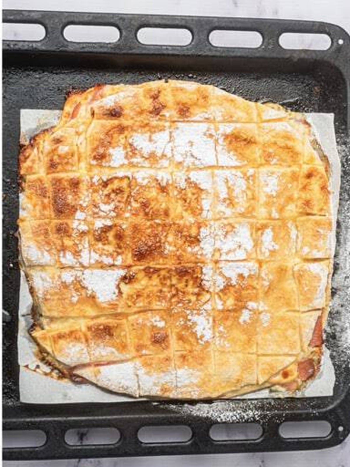 Golden baked Ham and Cheese Bars fresh from the oven dusted with powdered sugar.