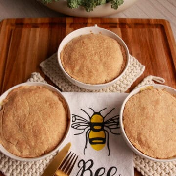Two Chedz cheesy chicken pot pies with golden cheddar crusts on a Bee Kind kitchen towel.