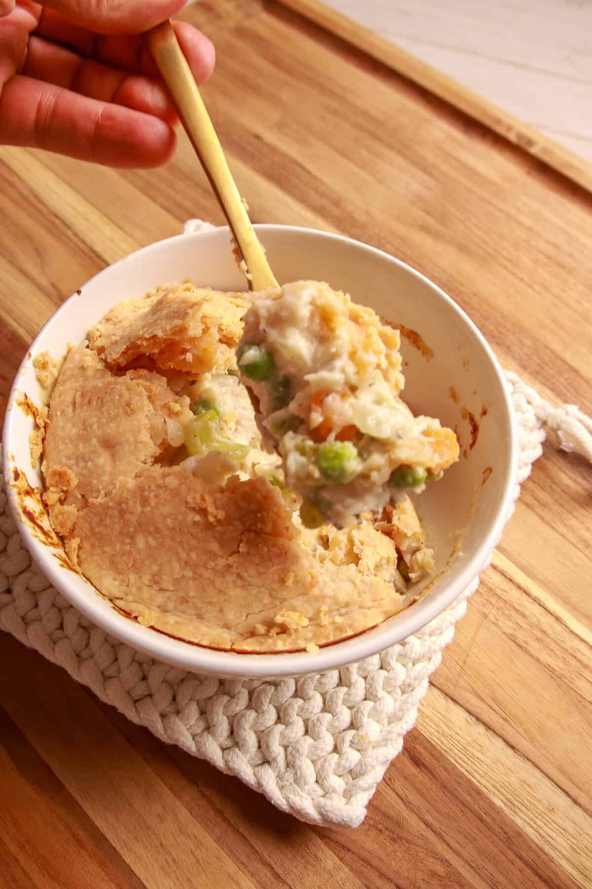 A spoonful of creamy Chedz cheesy chicken pot pie filling lifted from the baking dish.