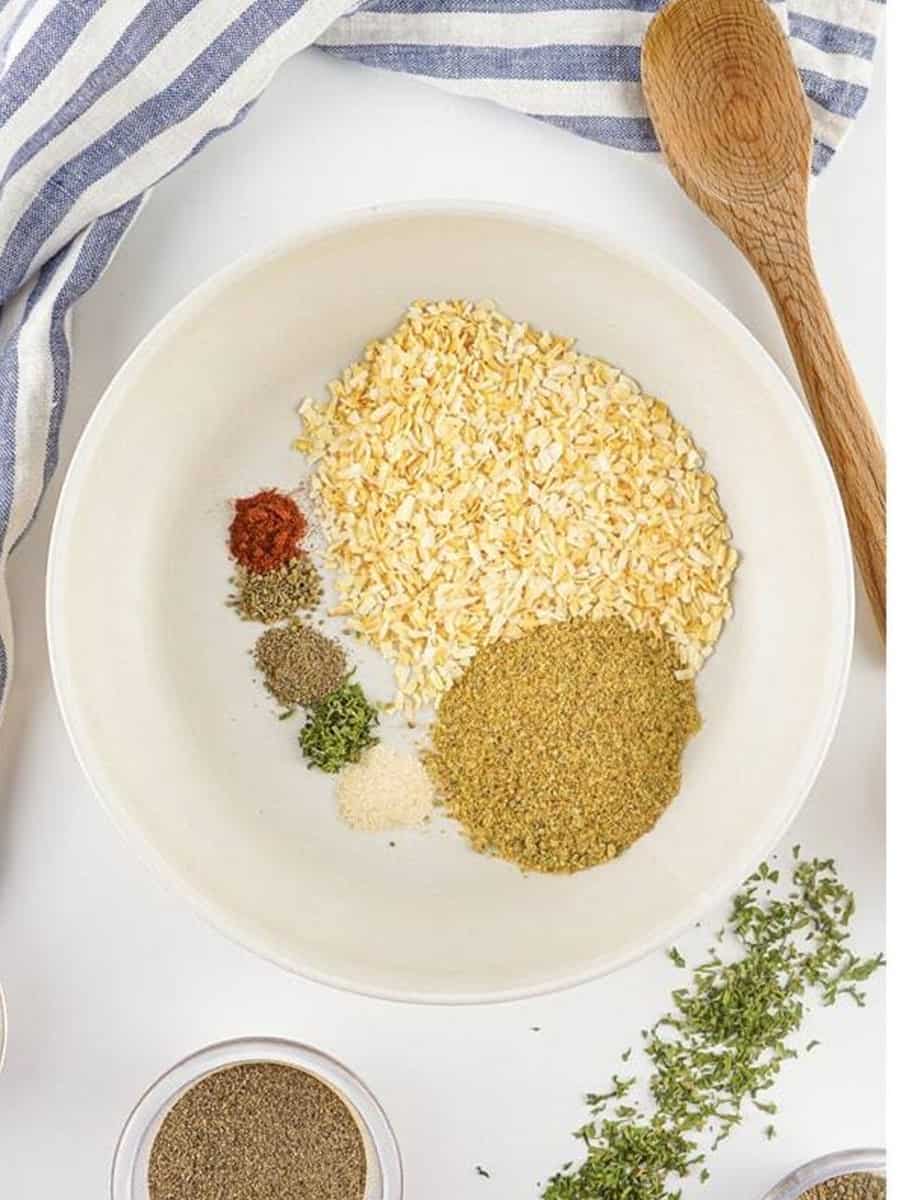 All the Homemade Onion Soup Mix spices added to a white mixing bowl.