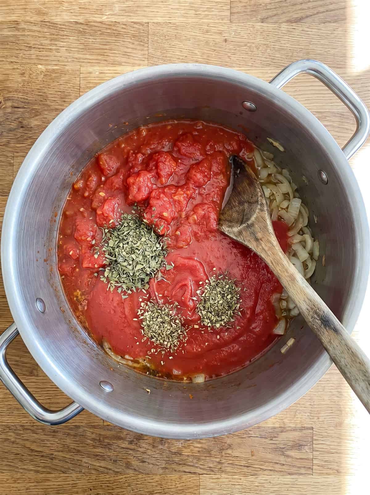Crushed tomatoes, tomato sauce, and dried herbs added to the pot for Homemade Pasta Sauce.