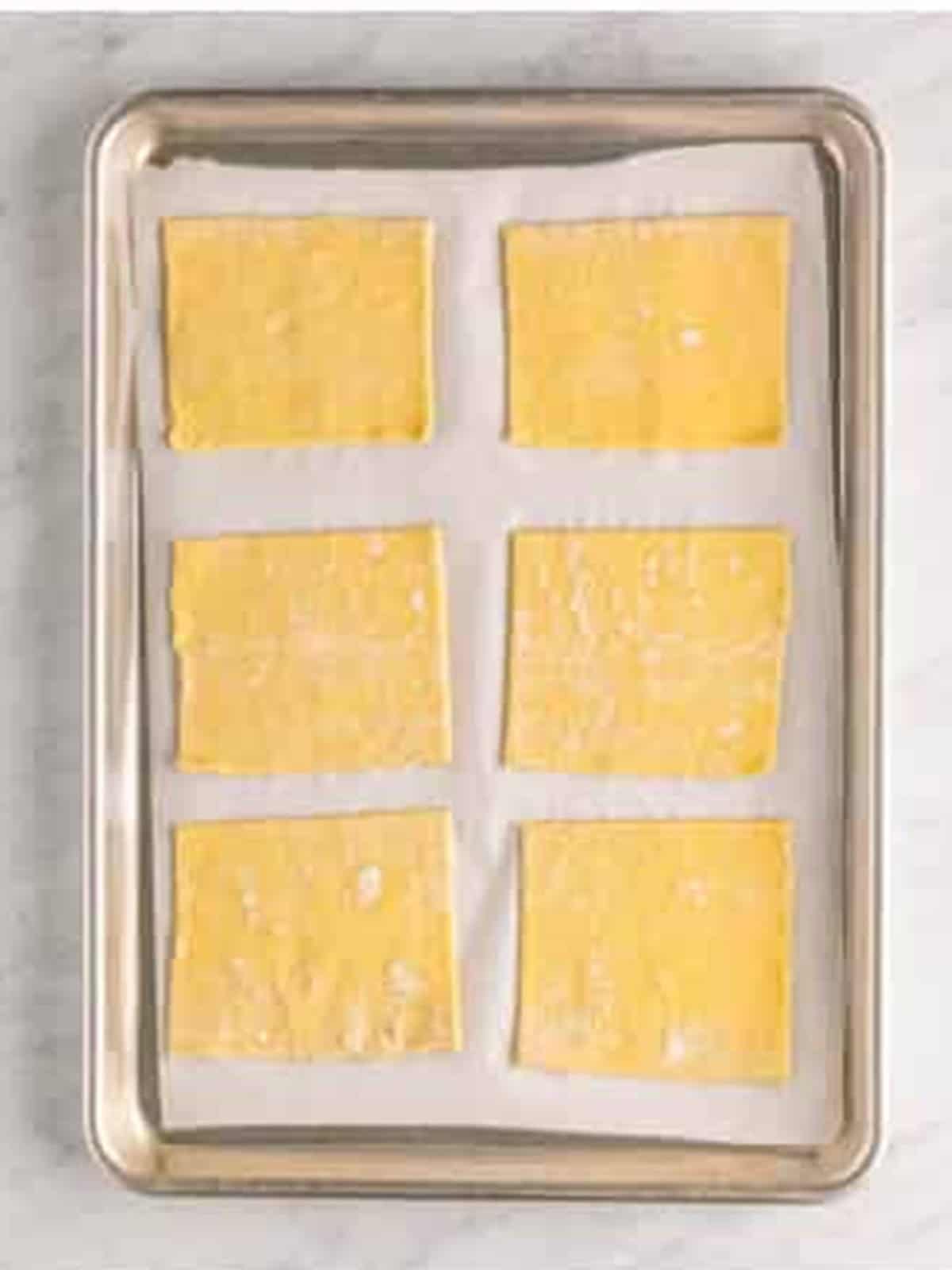 Puff pastry cut into rectangles arranged on a parchment lined sheet tray.