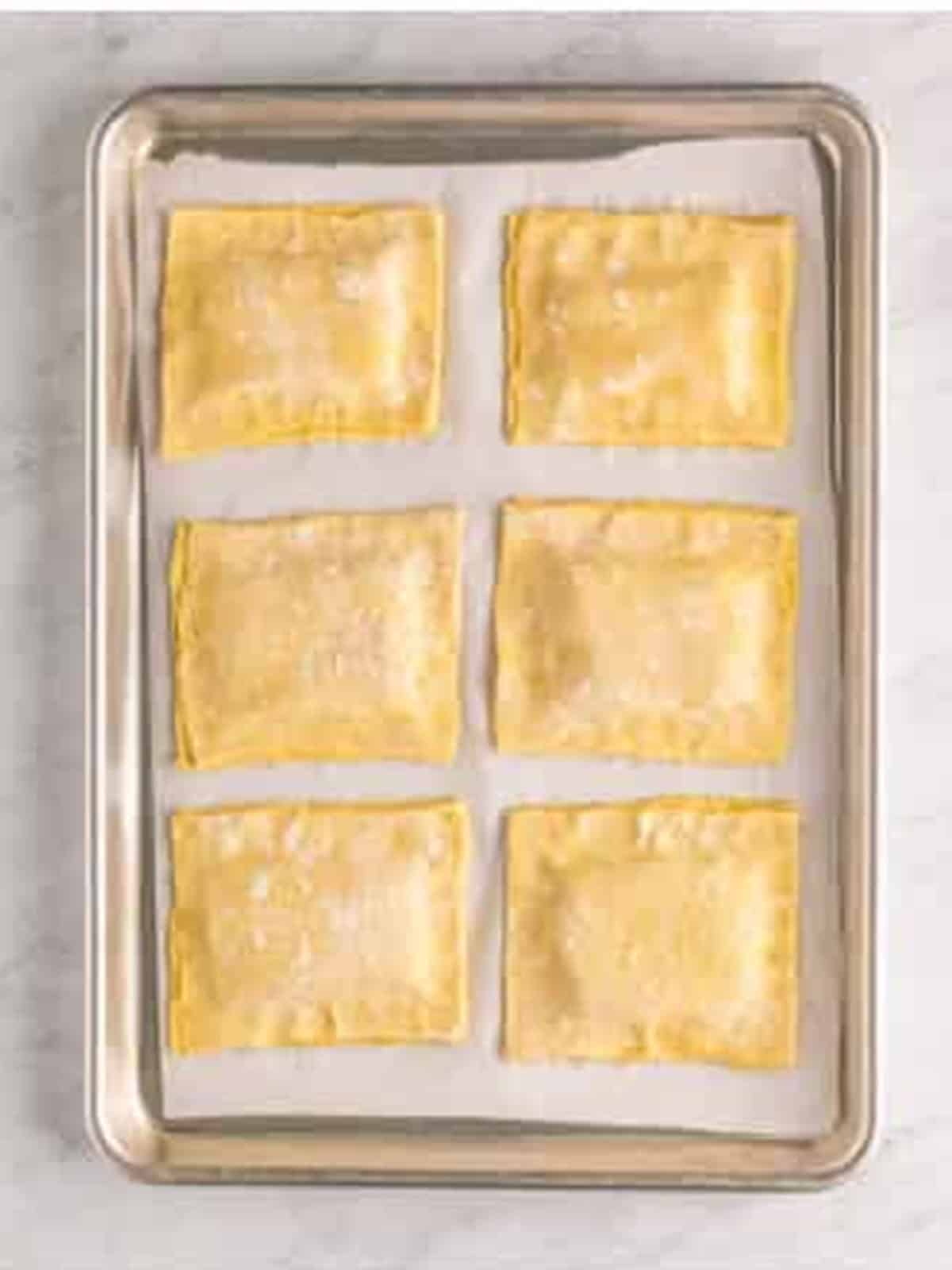 Puff pastry tops pressed and sealed over the apple filling before baking.
