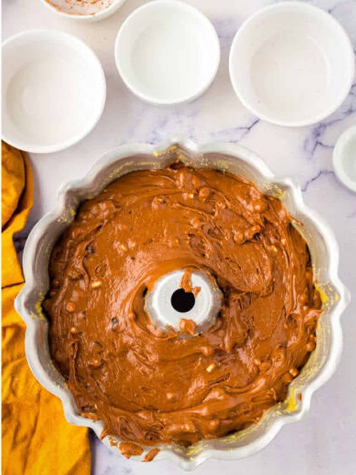 Hot chocolate cake batter spread into a buttered Bundt pan ready to bake.