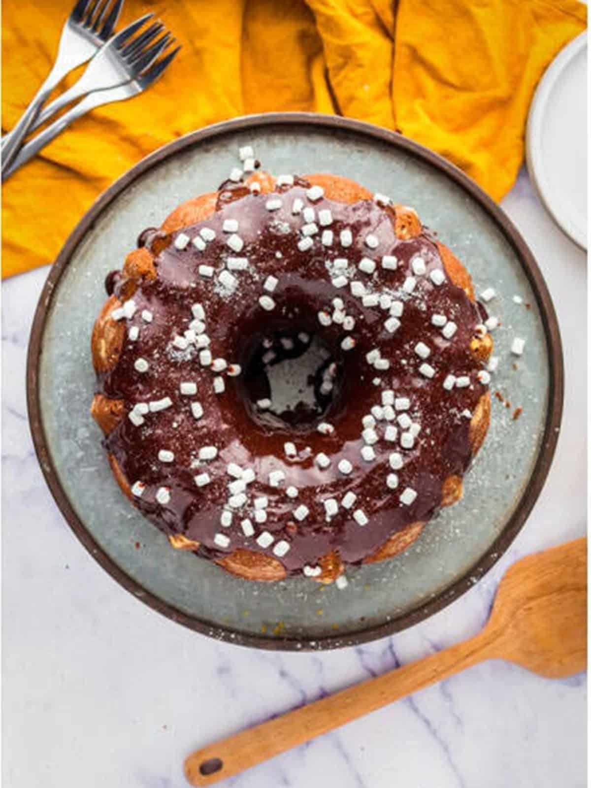 Baked hot chocolate Bundt cake topped with chocolate glaze and marshmallow bits.