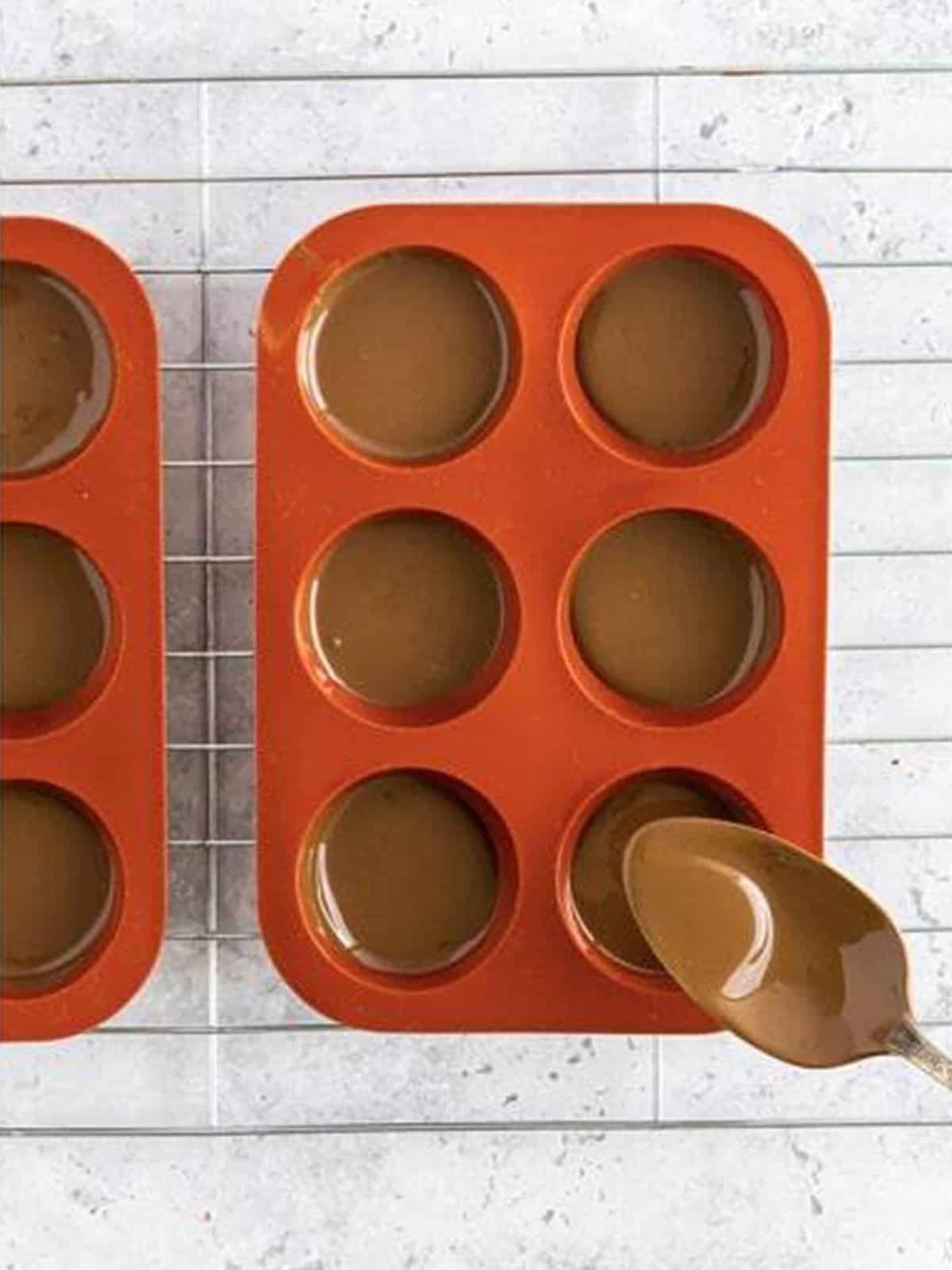 Melted chocolate spooned and swirled into the cavities of a red silicone bomb mold.