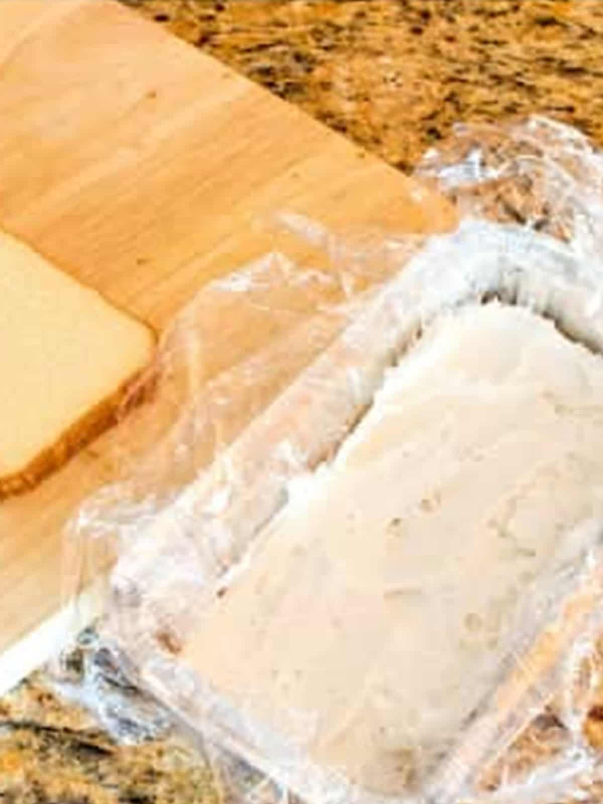 Softened vanilla ice cream spread over the bottom cake layer in a plastic lined loaf pan.