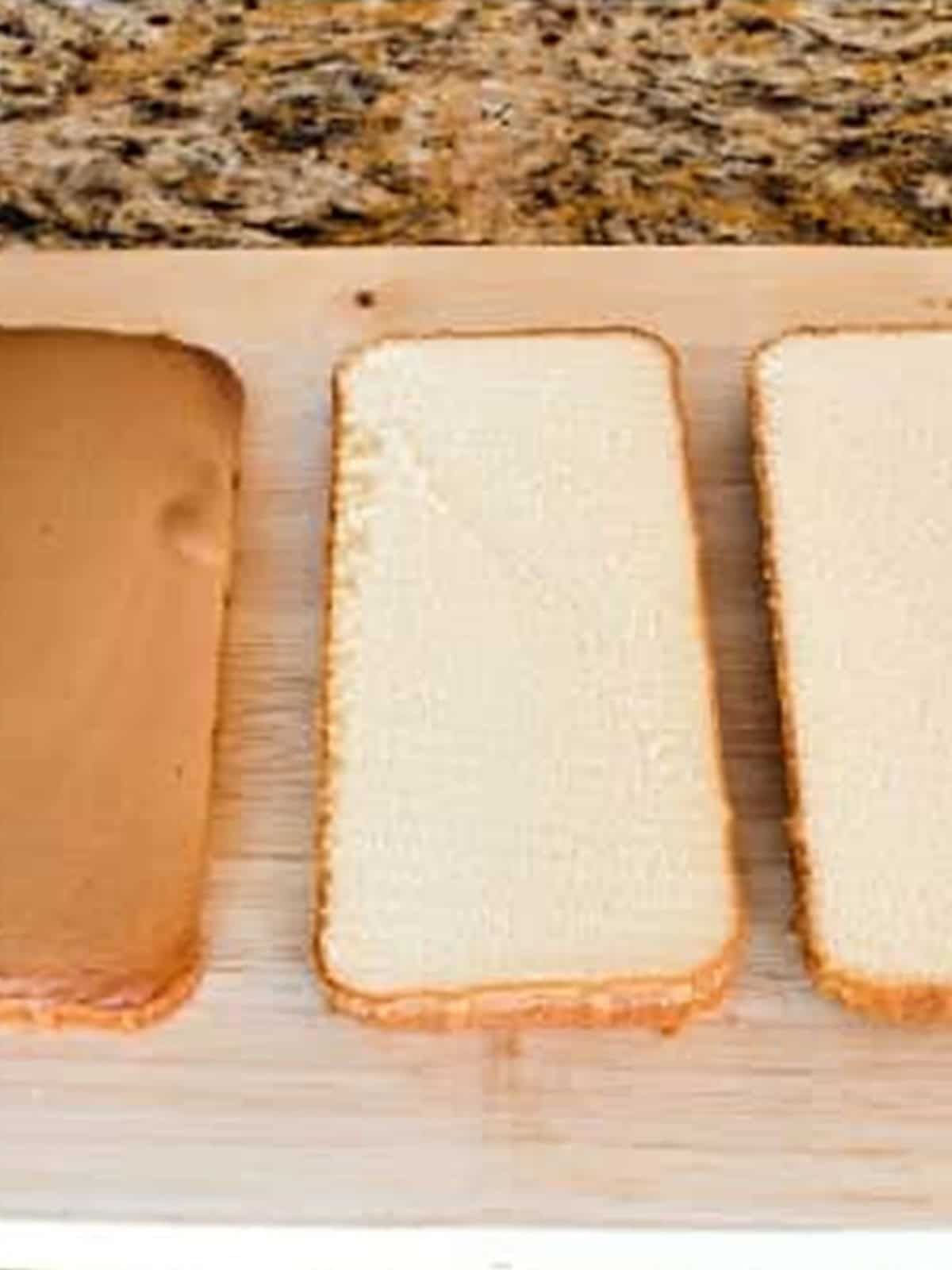 Pound cake sliced horizontally into three even layers on a wooden cutting board.
