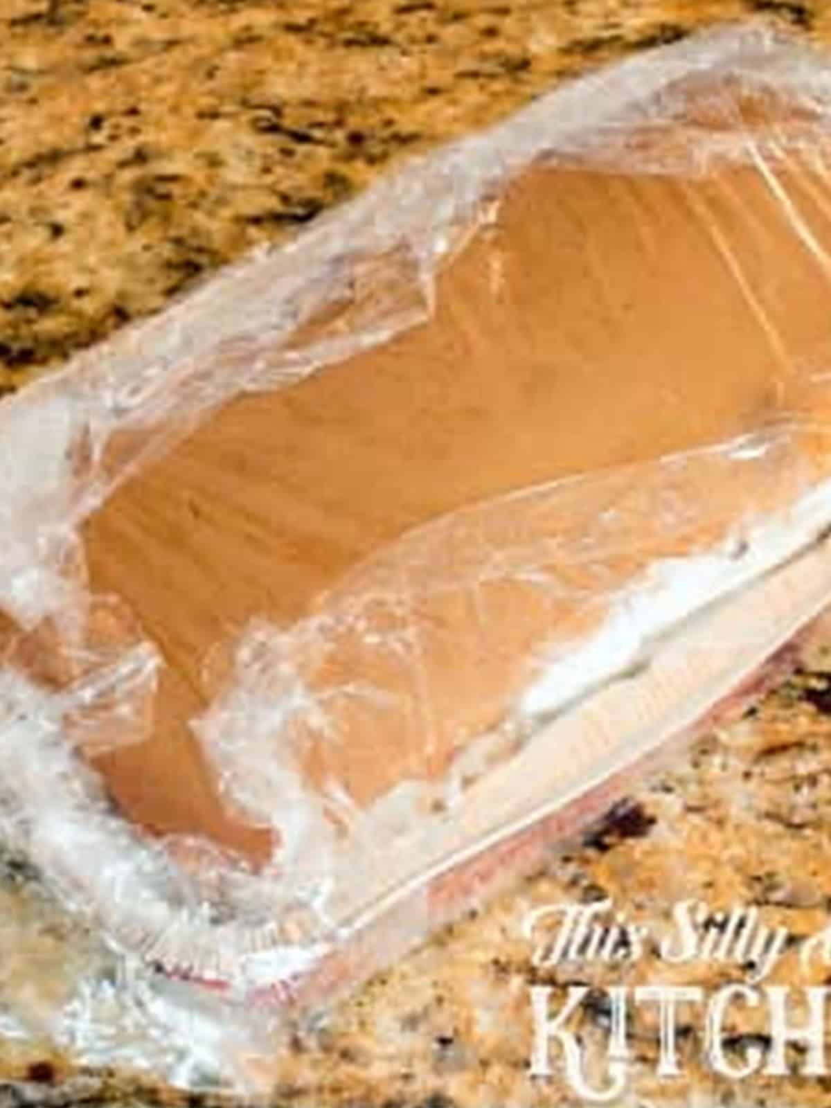 Assembled ice cream cake wrapped in plastic wrap in the loaf pan ready for the freezer.