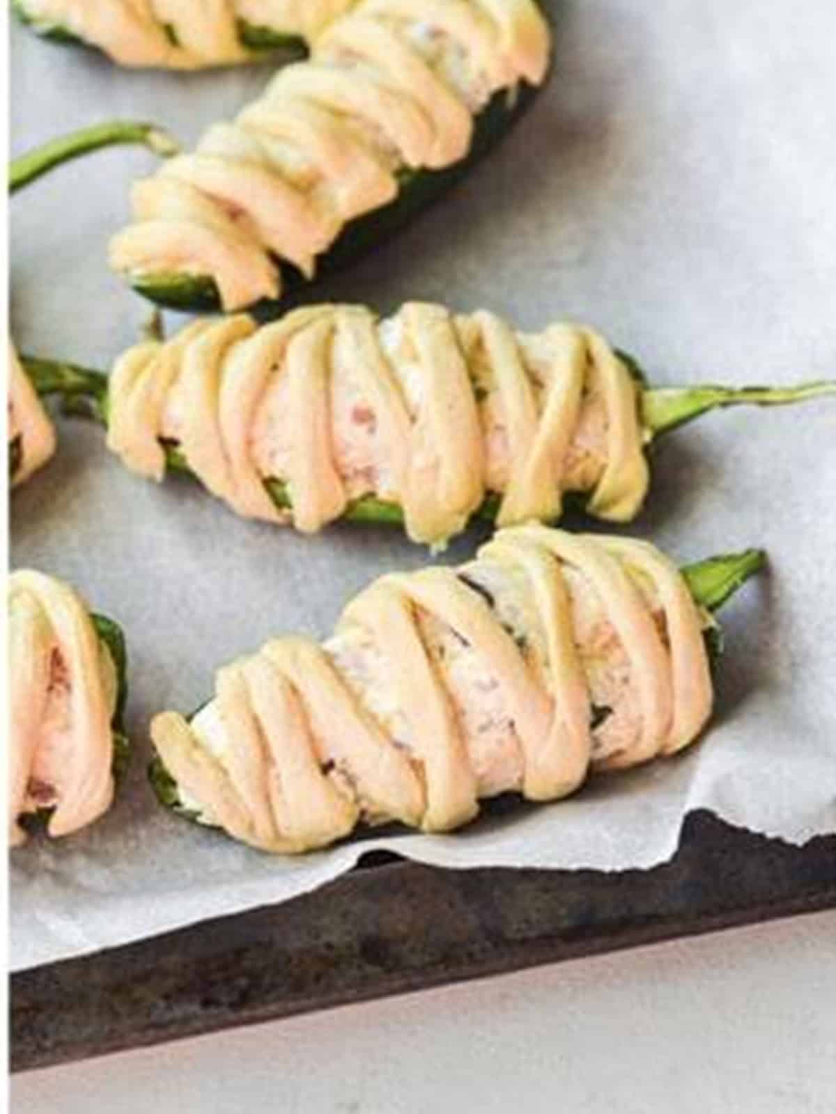 Filled jalapenos wrapped in crescent dough strips like mummies.