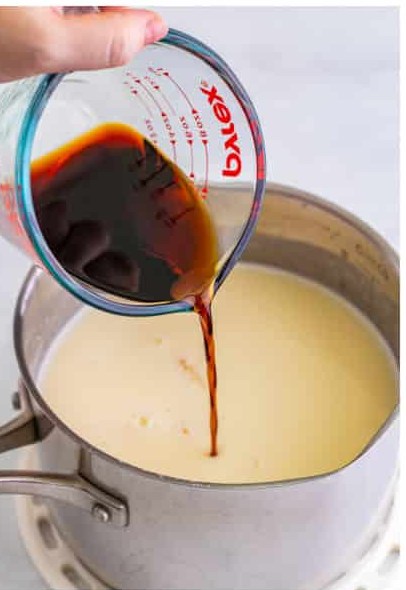 Kahlua coffee liqueur being poured into the melted white hot chocolate off the heat.