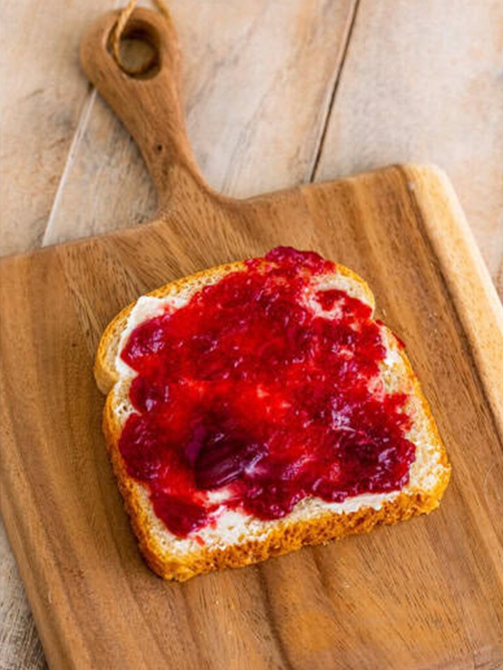 White bread smeared with mayonnaise and cranberry sauce as the base of the leftover turkey sandwich.