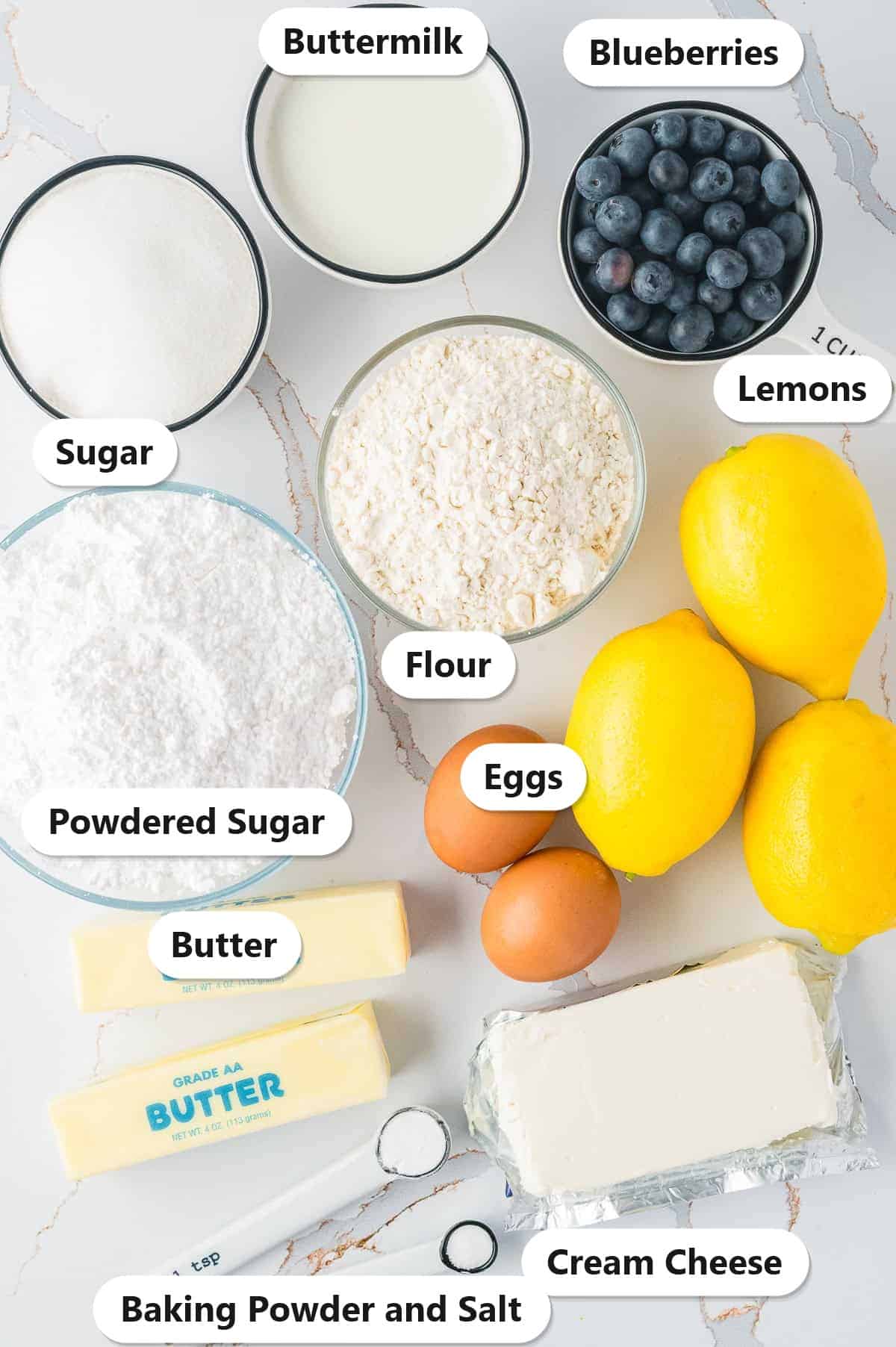 Labeled ingredients for Lemon Blueberry Cupcakes: flour, sugar, buttermilk, blueberries, lemons, eggs, butter, cream cheese, powdered sugar, baking powder and salt.