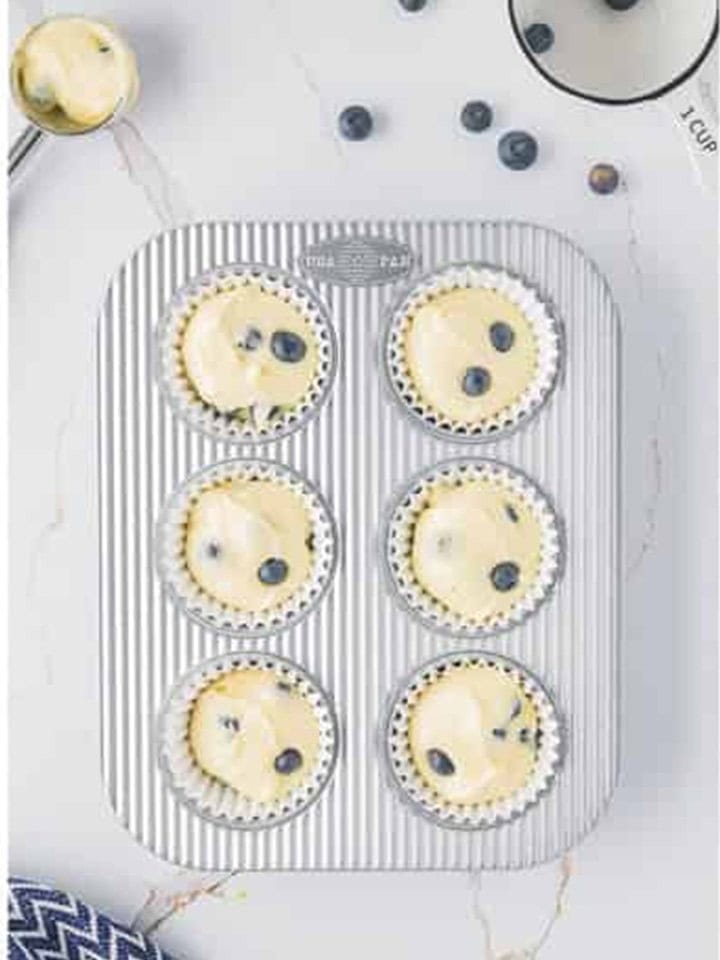 Cupcake liners filled with lemon blueberry batter ready to bake.