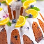A whole Lemon Blueberry Pound Cake drizzled with lemon glaze and topped with lemon slices and fresh blueberries.