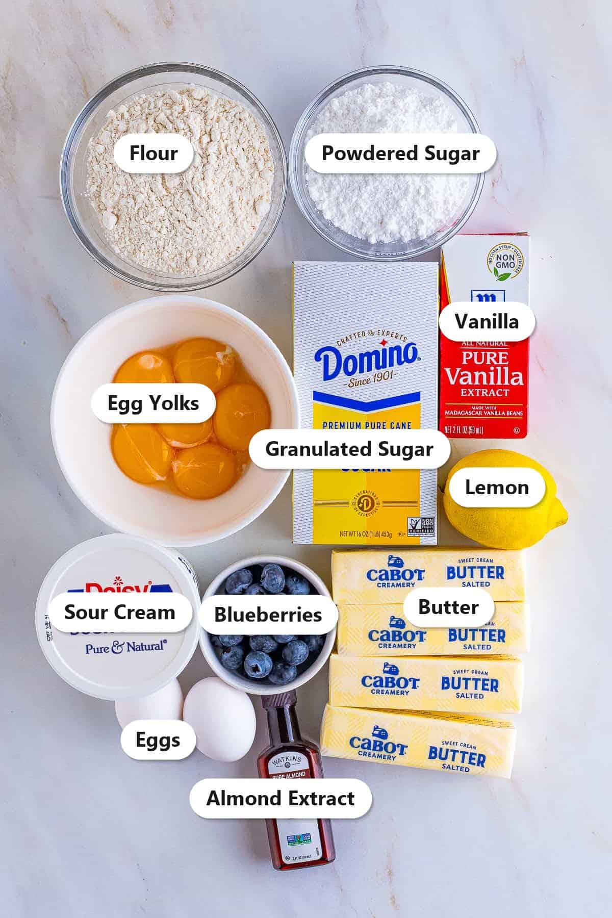 Labeled ingredients for Lemon Blueberry Pound Cake including butter, sugar, egg yolks, sour cream, lemon, and fresh blueberries.