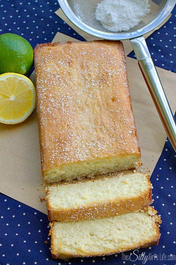 Glazed lemon lime cake on parchment with two slices cut showing the tender crumb.