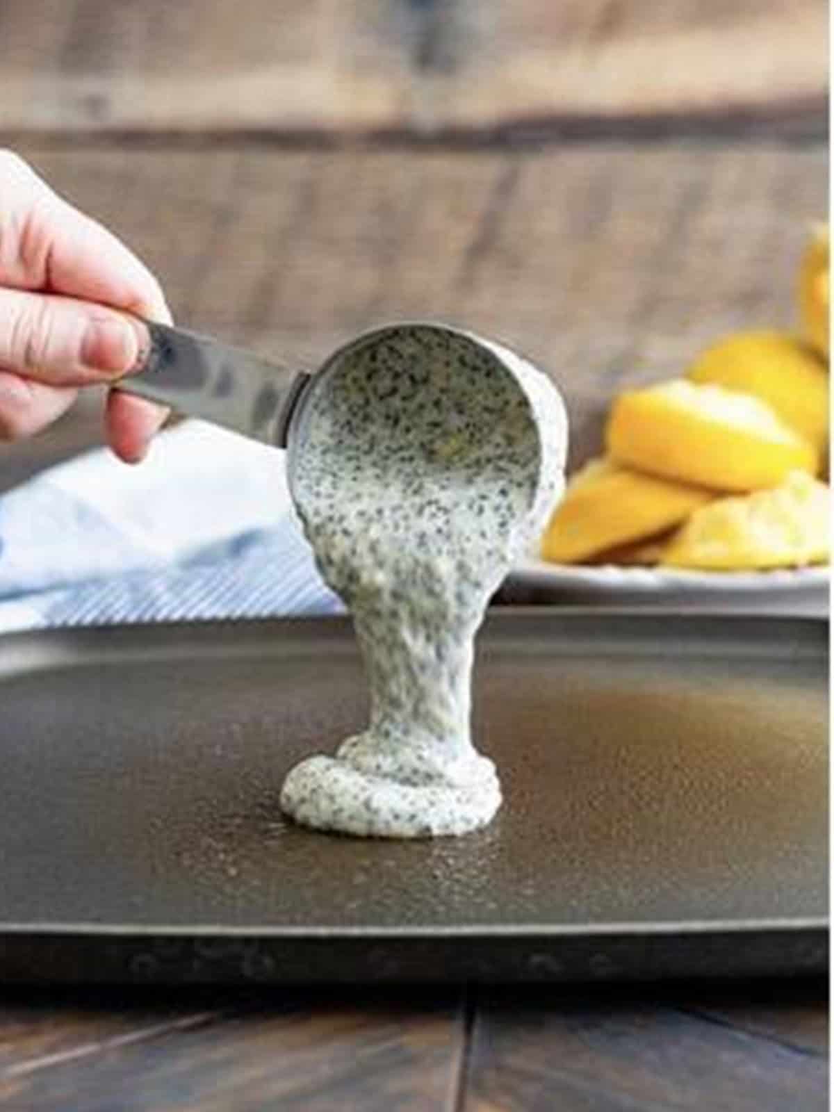 Lemon poppy seed pancake batter poured onto a hot griddle.