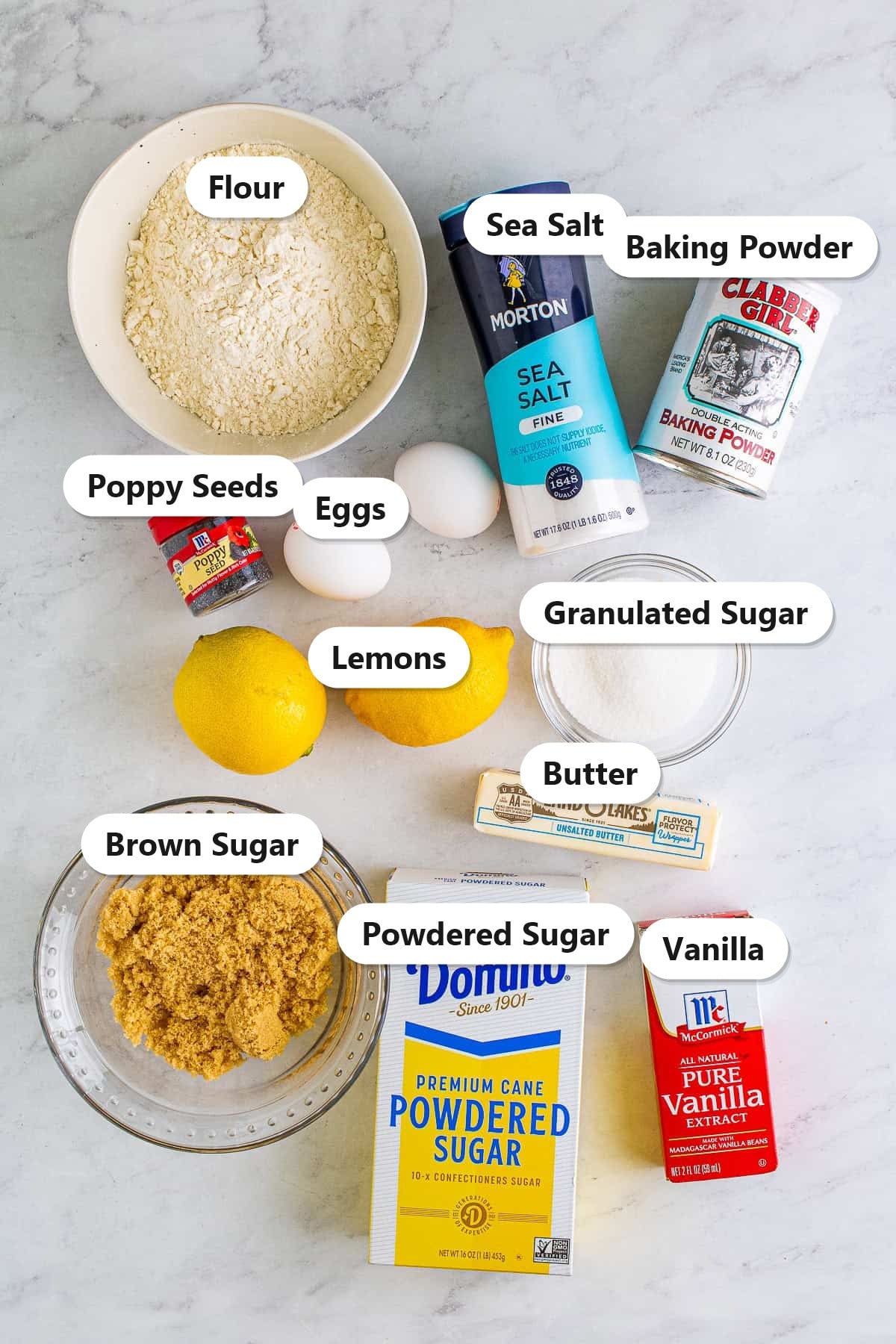 Labeled ingredients for lemon poppyseed bars including flour, poppy seeds, eggs, lemons, butter, brown sugar, granulated sugar, powdered sugar, baking powder, salt, and vanilla.