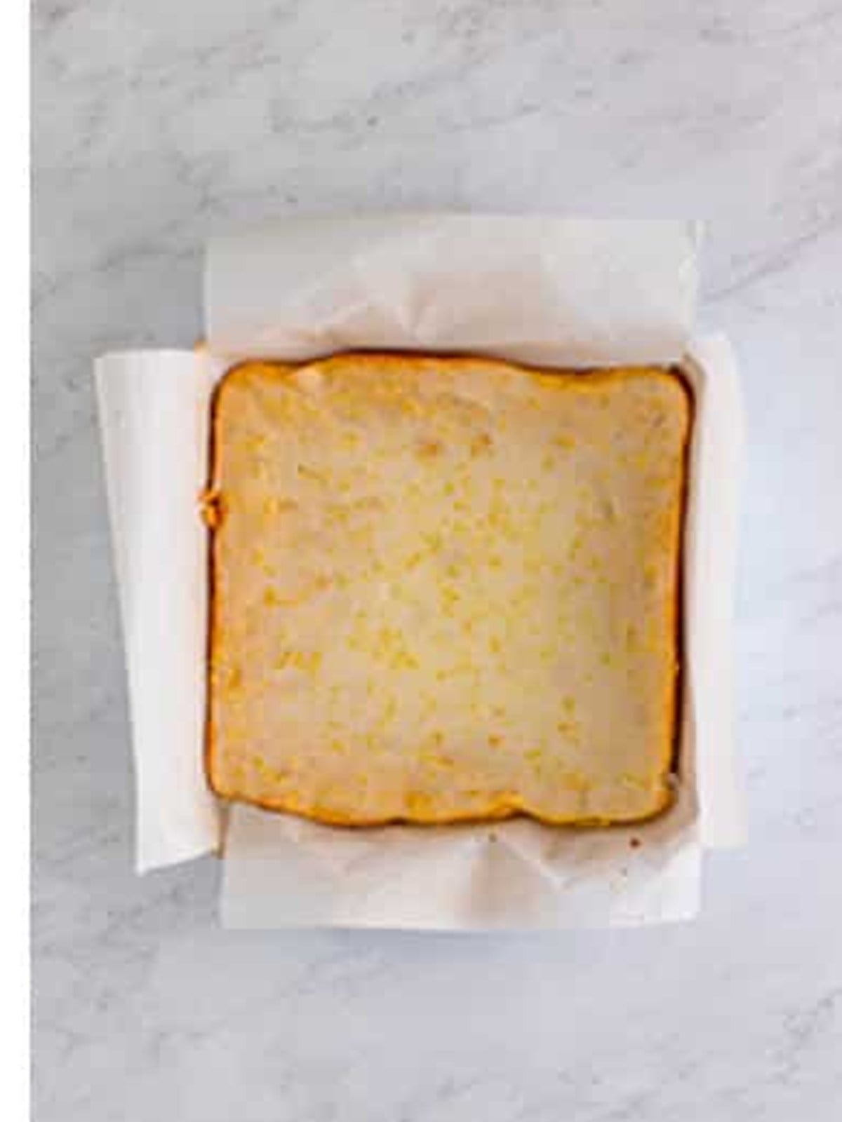 Lemon glaze poured and smoothed over the top of baked lemon poppyseed bars.