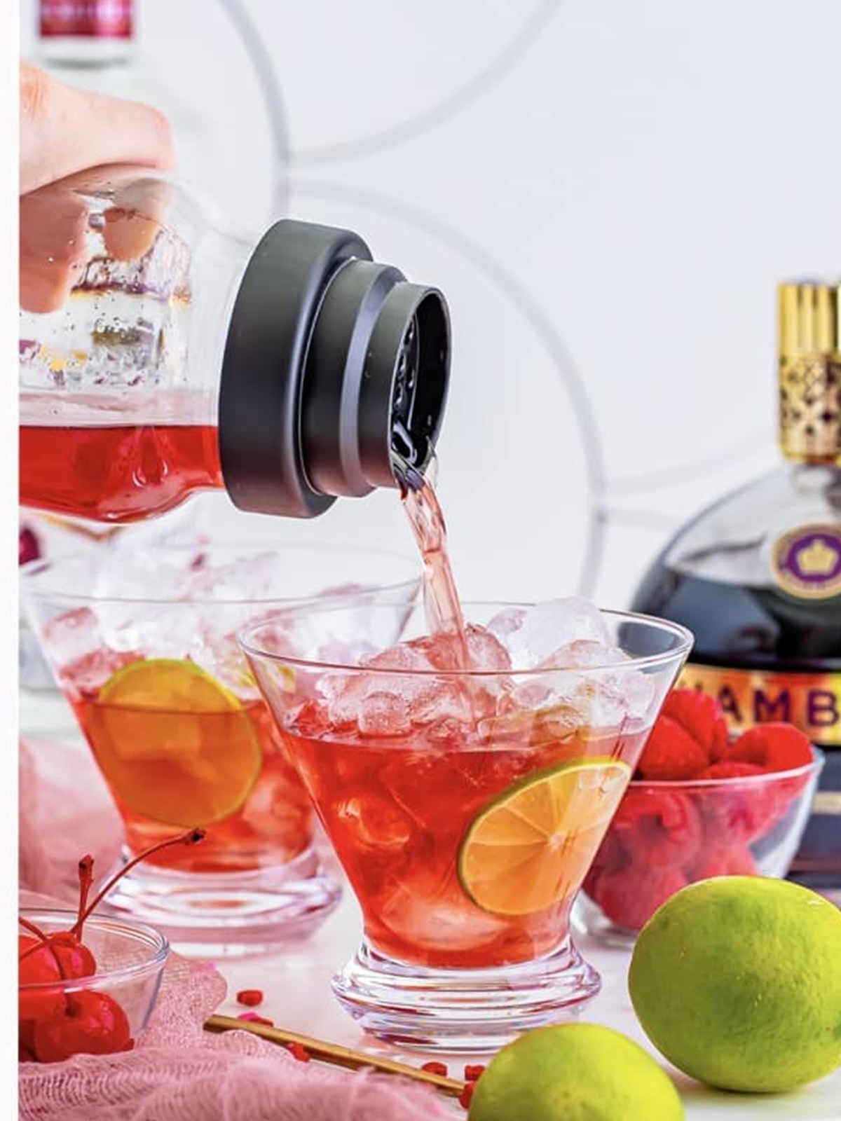 The red love potion cocktail poured from a shaker over ice into a martini glass.