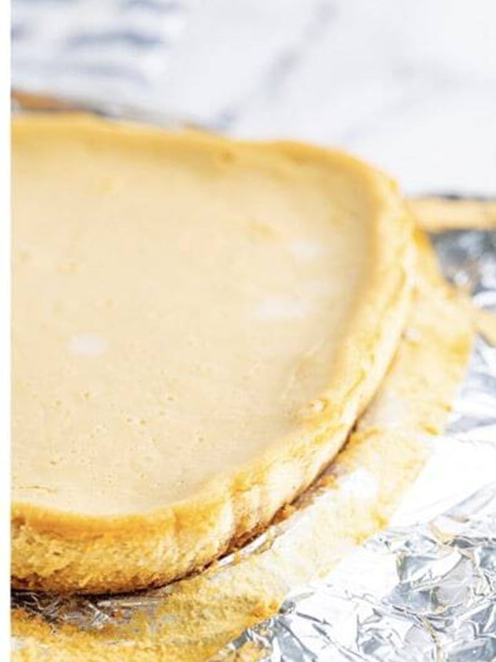 The baked maple cheesecake bars slab with a lightly golden top in the foil lined pan.