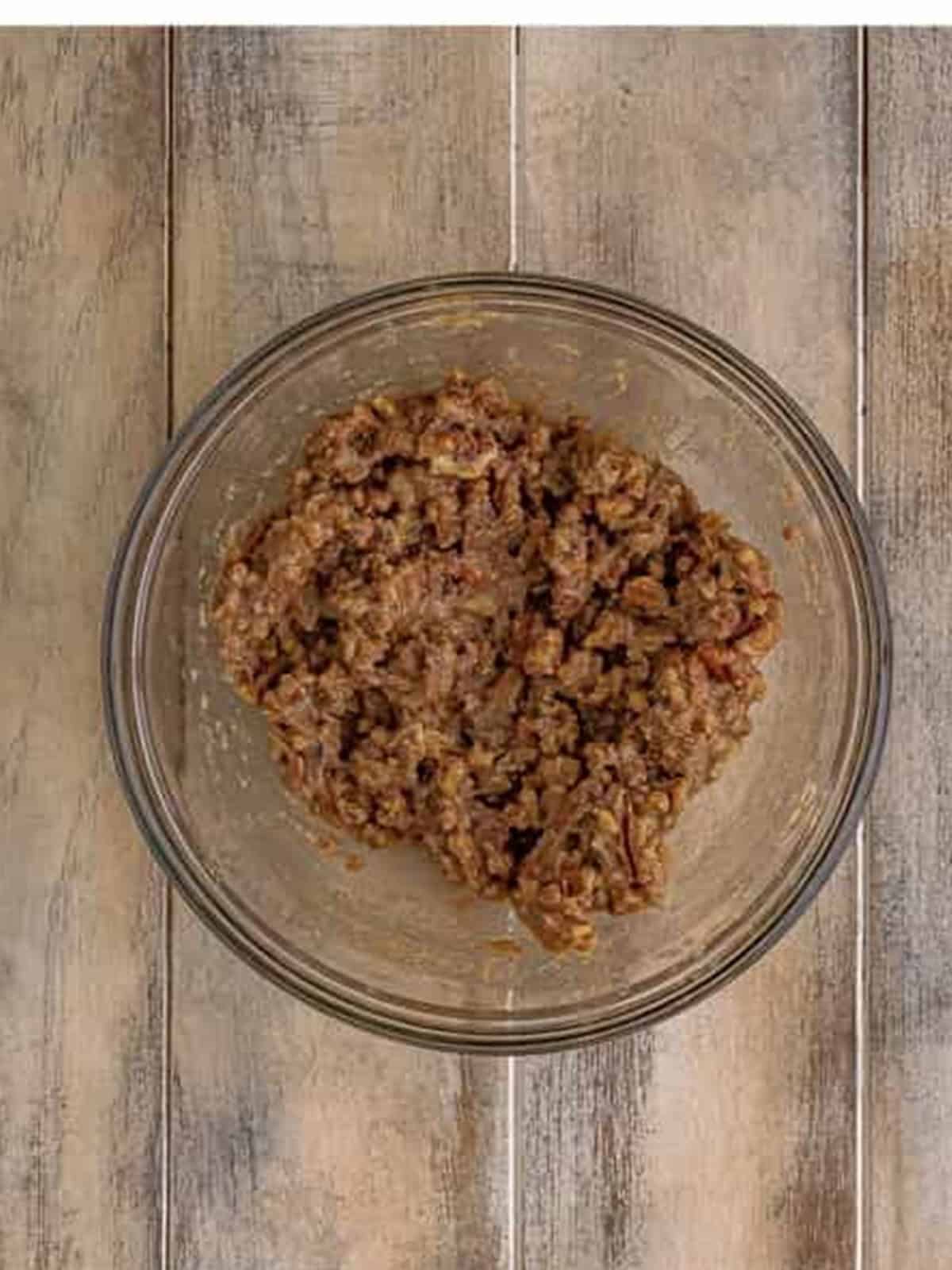 Maple pecan filling of brown sugar, butter, maple syrup, cinnamon, and chopped pecans mixed in a glass bowl.