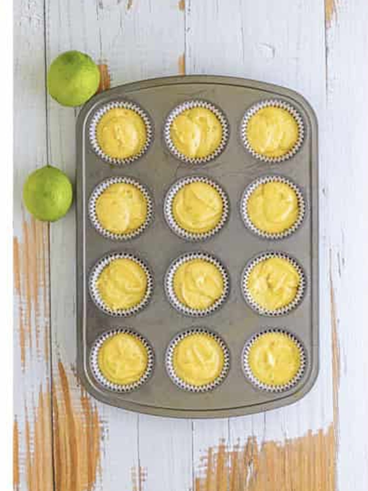 Margarita cupcake batter divided into a lined muffin tin.