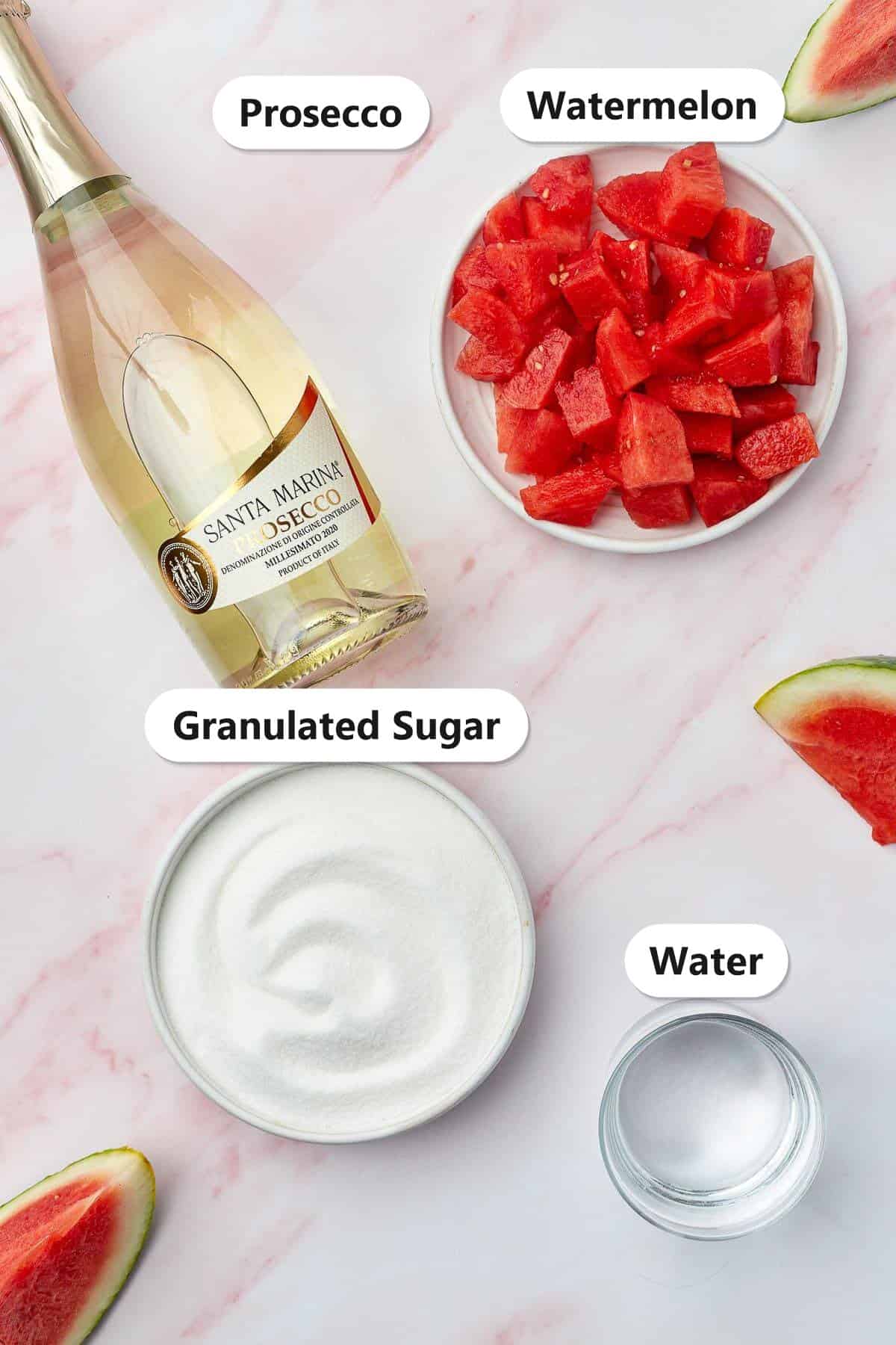 Melon Cocktail ingredients laid out and labeled including prosecco, diced watermelon, granulated sugar, and water.