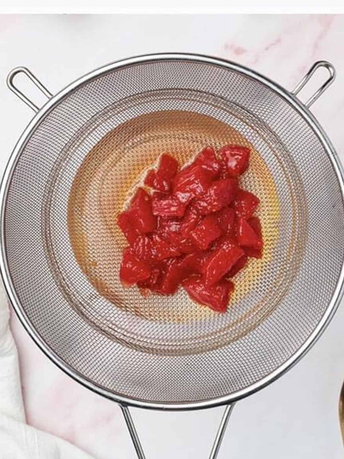 Watermelon syrup straining through a mesh strainer for the Melon Cocktail.