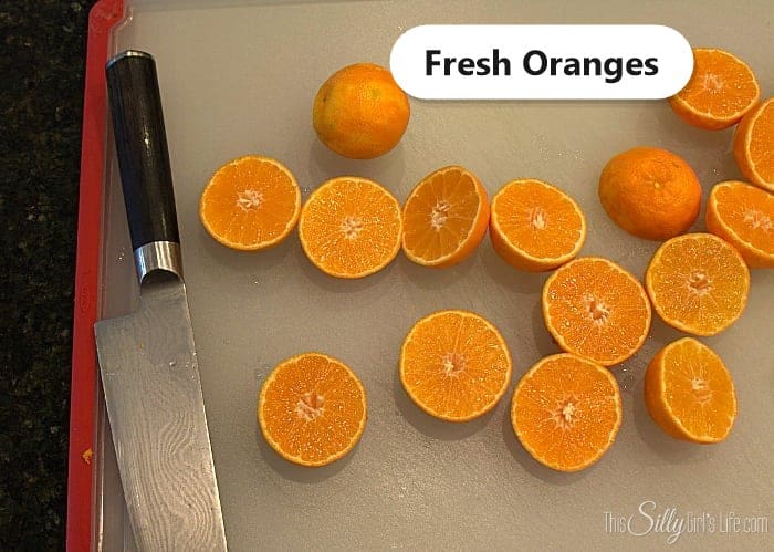 Fresh oranges cut in half on a cutting board for mimosa cupcakes, labeled.