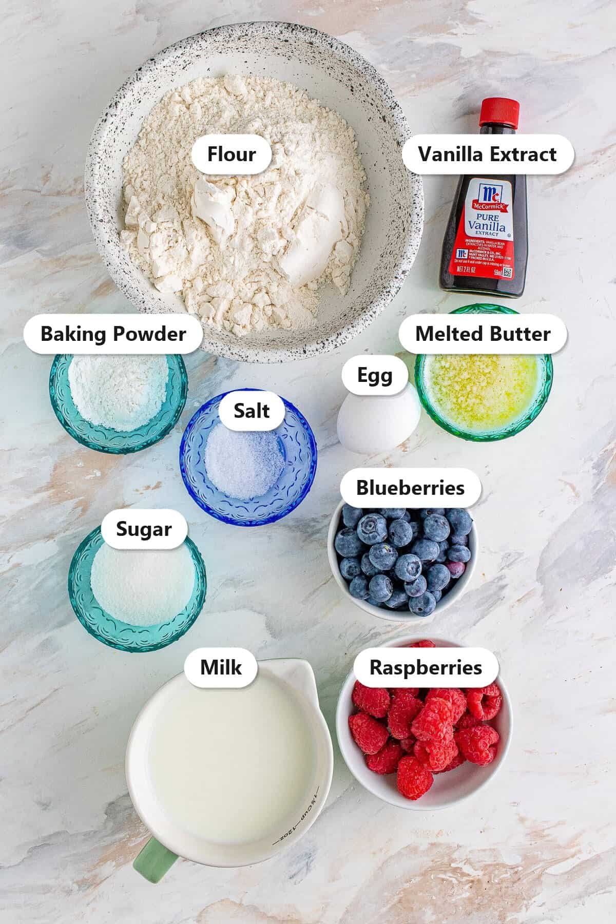 Labeled ingredients for mini berry pancake bites including flour, milk, egg, butter, blueberries, and raspberries.