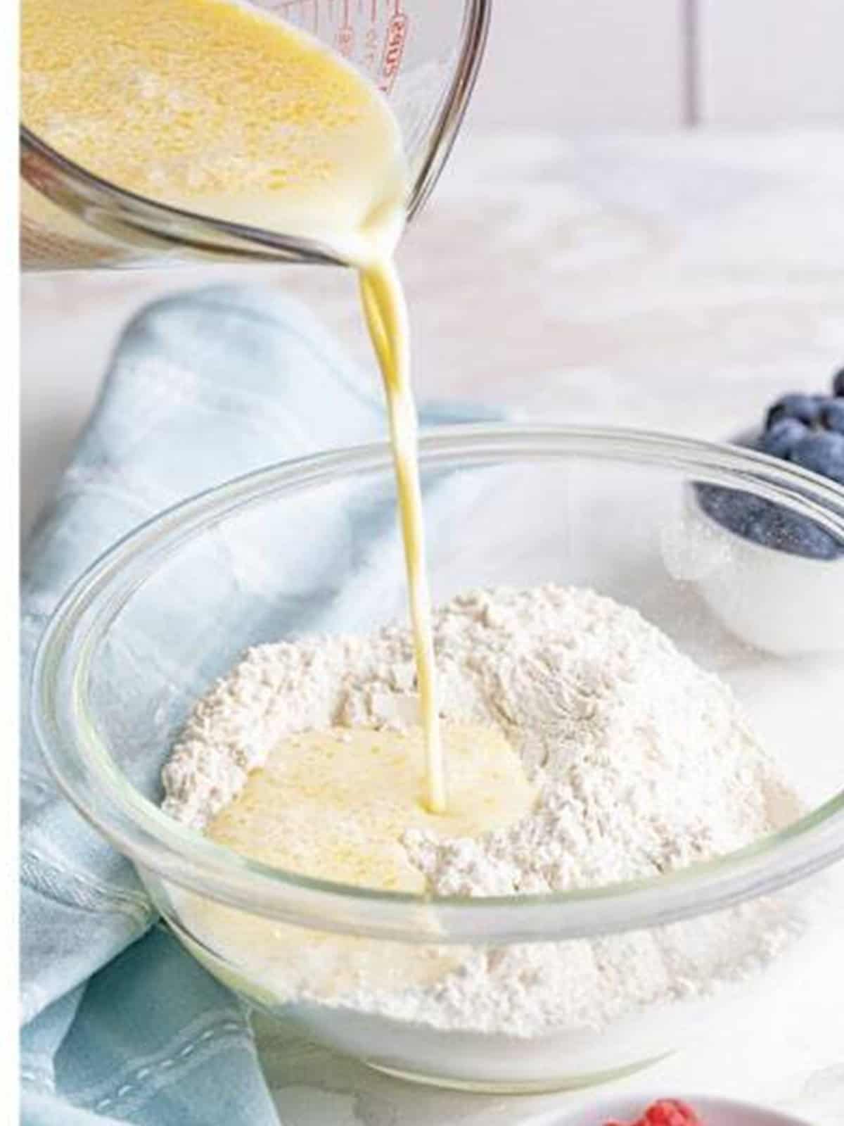 Wet batter ingredients being poured into a bowl of dry pancake mix.