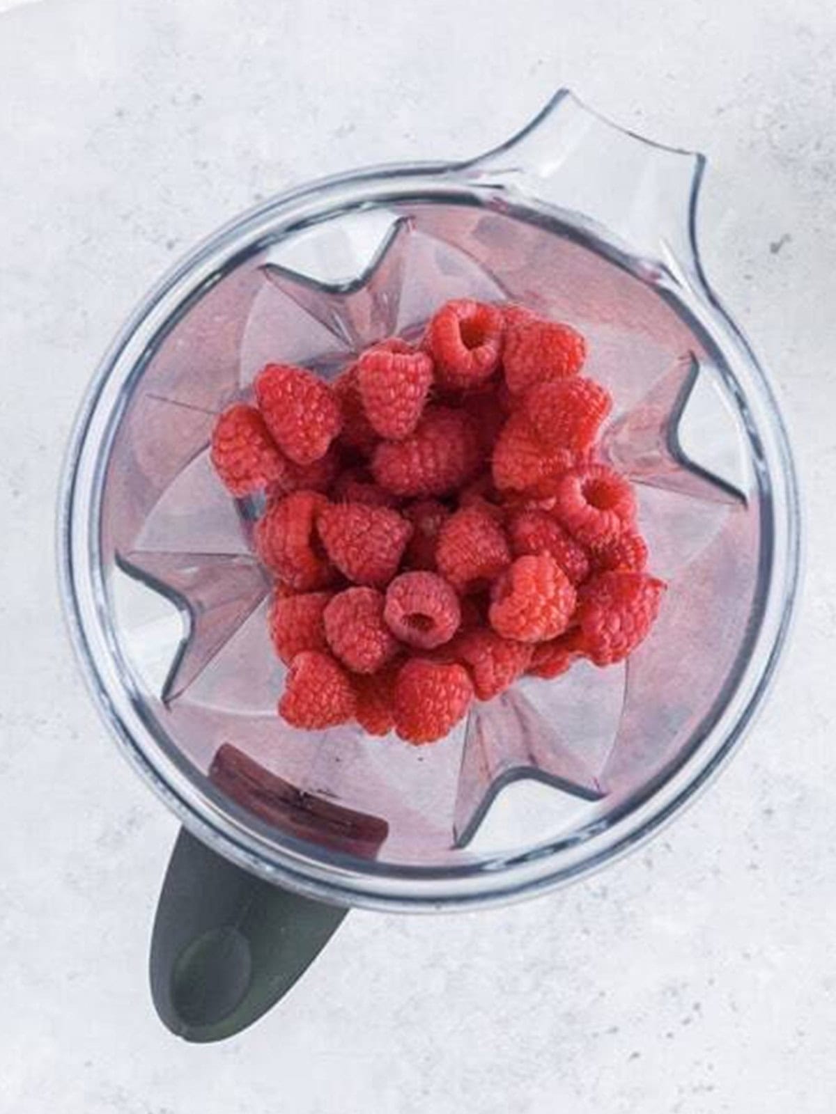 Fresh raspberries blended smooth in a blender for mini lemon cheesecakes.
