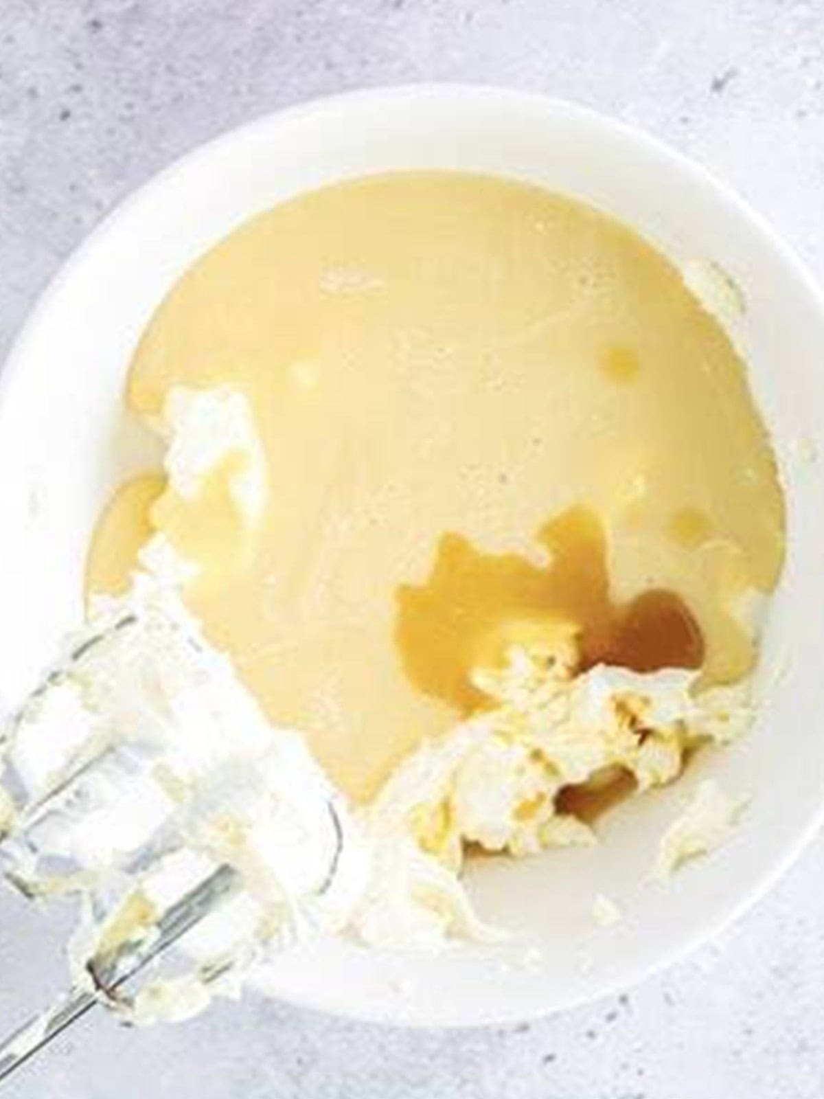 Sweetened condensed milk and vanilla mixed into whipped cream cheese for mini lemon cheesecakes.