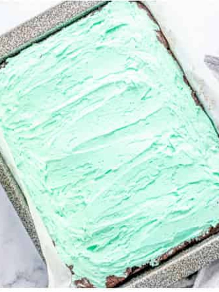 Green mint frosting spread in an even layer over the cooled brownies.