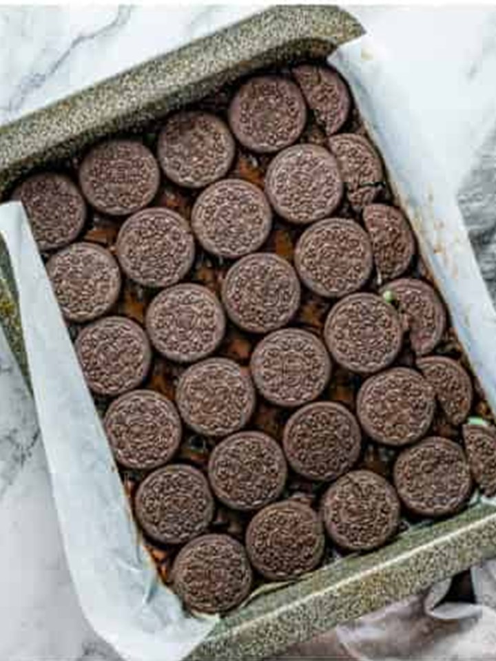 Mint Oreo cookies layered over half the brownie batter in the pan.
