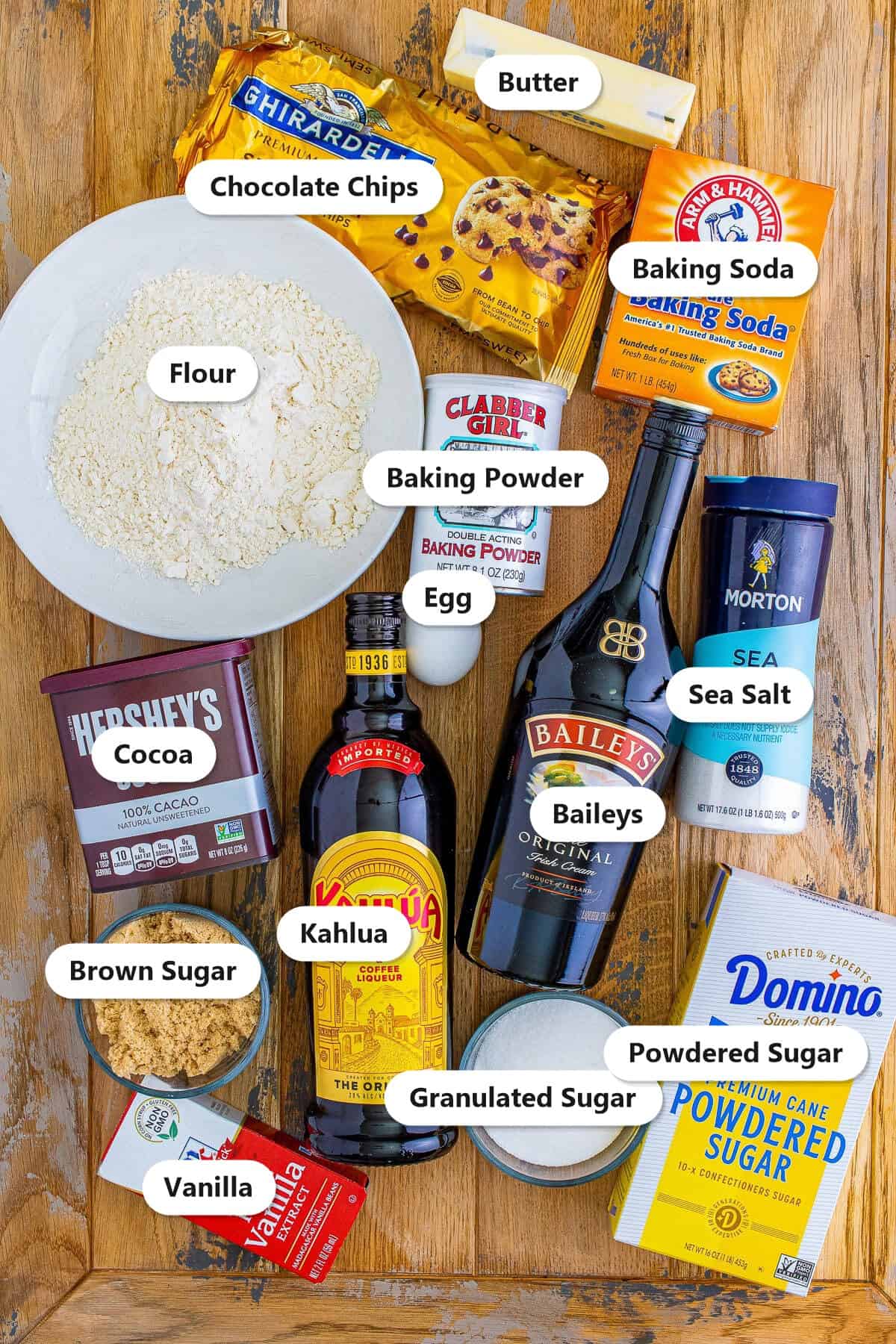 Labeled ingredients to make mudslide chocolate cookies including flour, cocoa, chocolate chips, Kahlua, Baileys, butter, sugars, and vanilla.