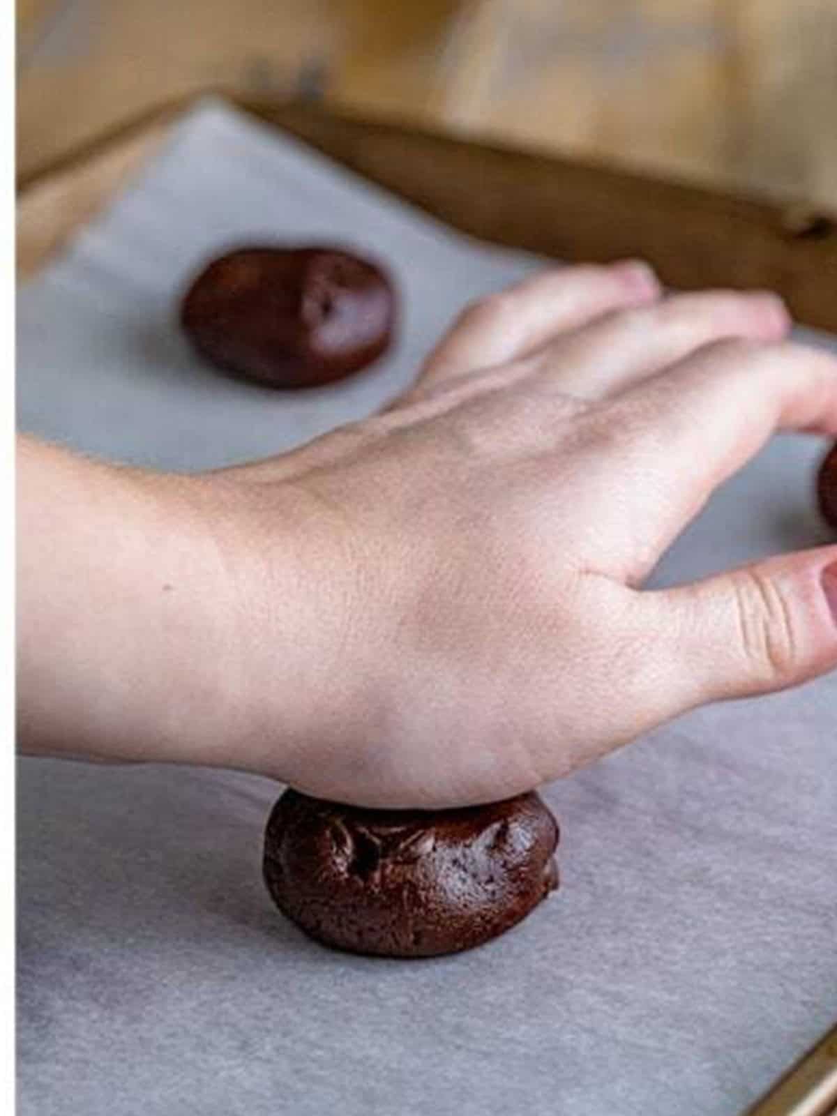 A mudslide cookie dough ball flattened on parchment paper.
