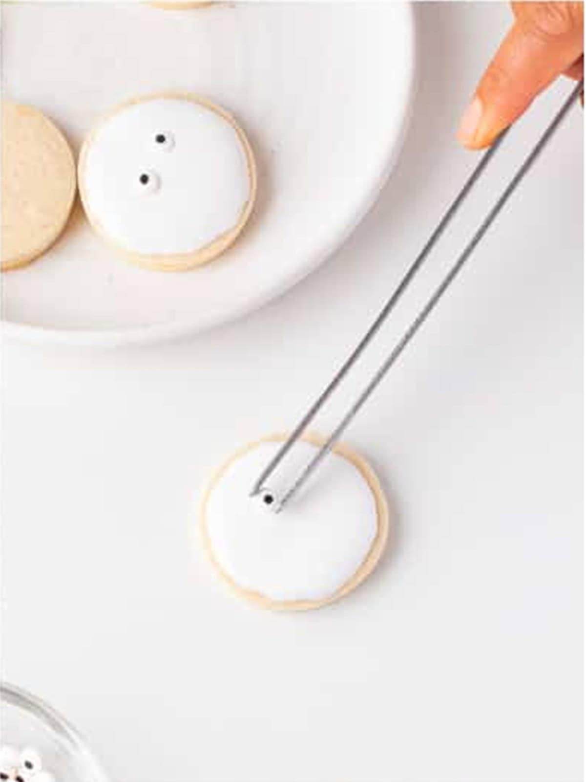 Candy eyes placed onto the flooded royal icing base of a mummy cookie.