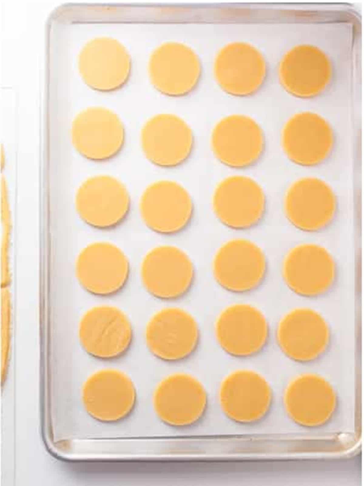 Round mummy cookies cut and arranged on a parchment lined baking sheet.