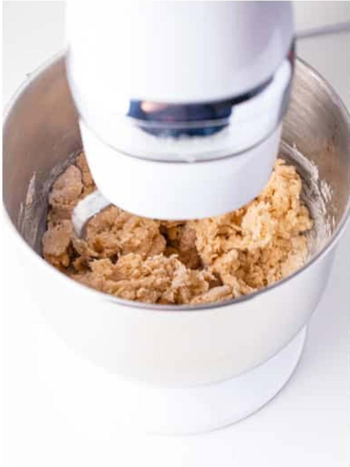 Sugar cookie dough for mummy cookies mixing in a stand mixer with a paddle attachment.