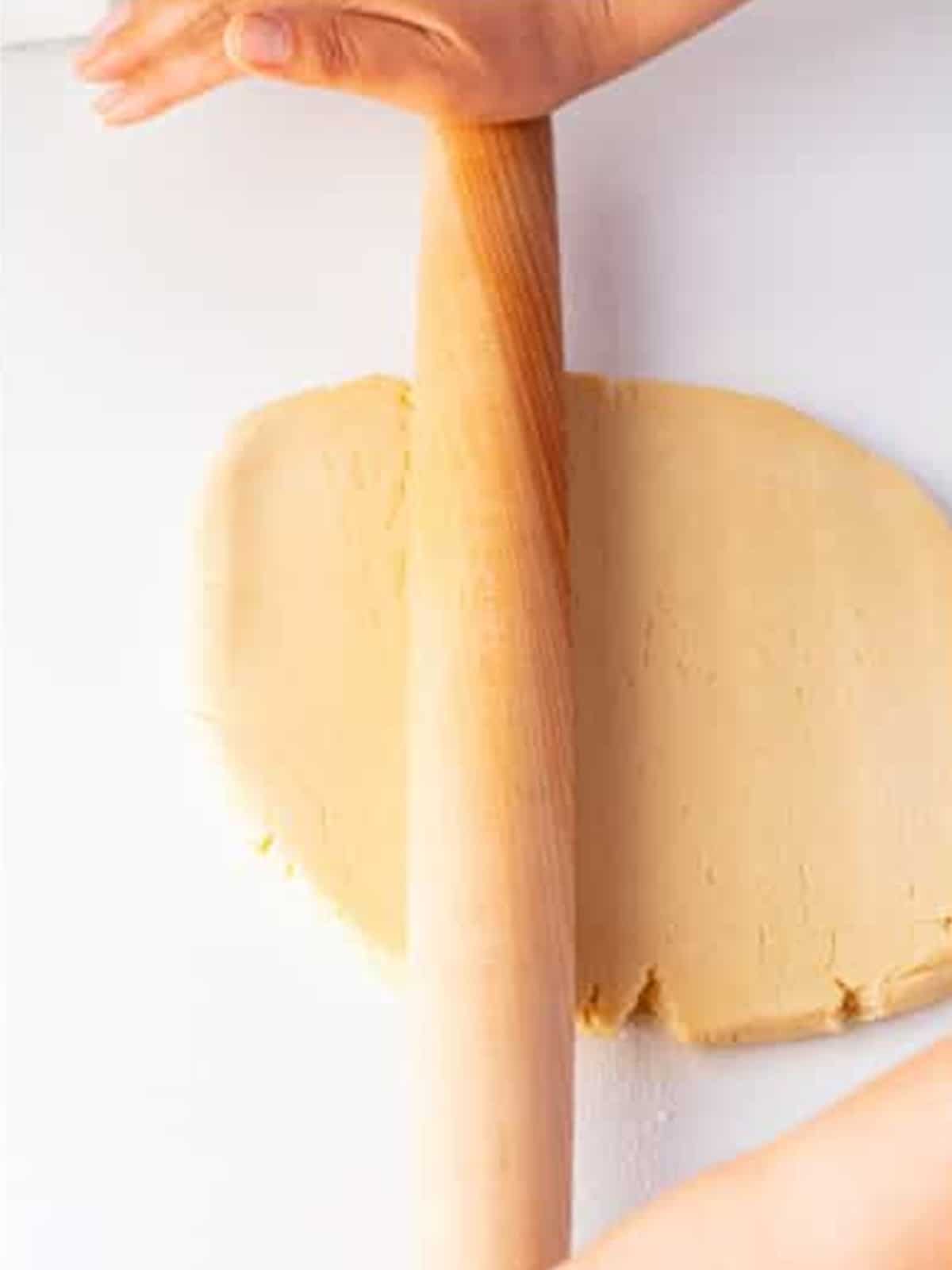 Rolling the mummy cookies dough into an even quarter inch sheet with a rolling pin.