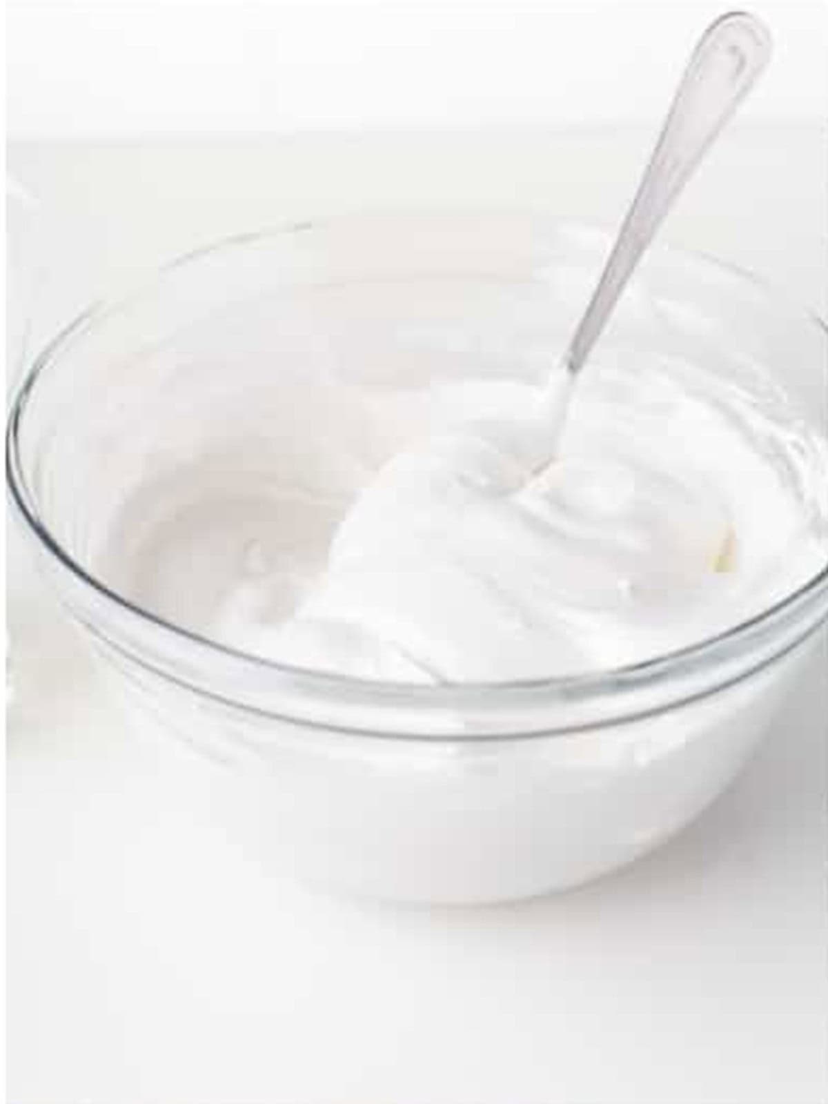Fluffy white royal icing whipped in a glass bowl for decorating mummy cookies.
