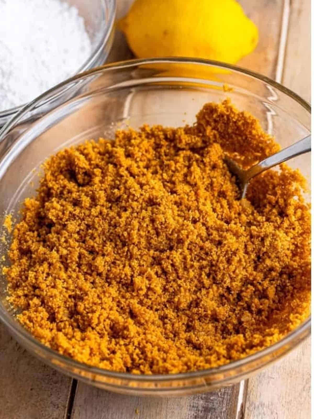 Graham cracker crumbs, melted butter, and sugar stirred together in a glass bowl for the crust.